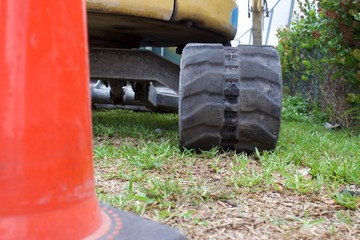 Wall Mural - ground view of mini excavator track behind traffic cone