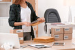 © Africa Studio - Young woman preparing parcel envelopes for shipment to client in home office