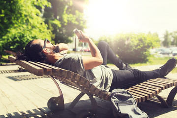 Sticker - people, music, technology, leisure and lifestyle - hipster man with smartphone and earphones listening to music lying on city street bench