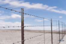 Barb Wire Fence In The Dry Desert Country With Metal Post