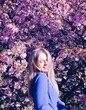 © Vladimir - Happy young blonde woman in blue coat enjoying sakura blossom season