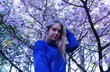 © Vladimir - Portrait of young blonde woman in blue coat posing near flowering sakura tree