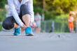 © Jo Panuwat D - young fitness woman legs walking in the park outdoor, female runner tying running shoes, asian girl jogging and exercise on footpath in sunlight morning. healthcare and well being concepts