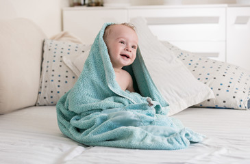 Wall Mural - Portrait of cute smiling baby boy covered in big blue towel