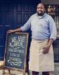 © Rawpixel.com - A cheerful business owner standing with open blackboard