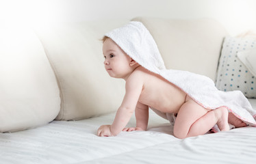 Wall Mural - Cute baby boy with towel with hood on head crawling on bed