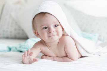 Wall Mural - Cute 9 months old baby son lying under white towel on bed