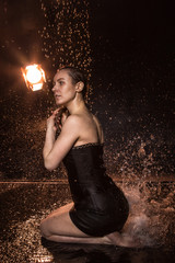 Wall Mural - Girl in black dress in water in a small pool, drops of water and dark background