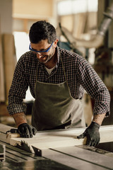 Wall Mural - Skilled carpenter cutting a piece of wood in his woodwork workshop