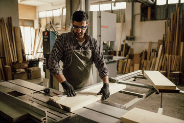 Wall Mural - Skilled carpenter cutting a piece of wood in his woodwork workshop