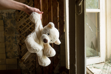 A toy bear on a windowsill in an empty abandoned apartment. Apocalypse, war, idea