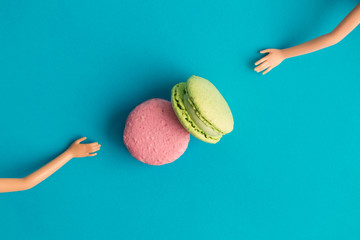 Wall Mural - Flat lay of colorful macarons and doll hands abstract concept.