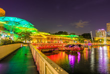Clarke Quay Bridge And Riverside Area At Evening In Singapore, Southeast Asia. Waterfront Skyline Reflected On Singapore River. Popular Attraction For Nightlife.