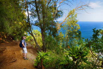 Poster - Young male tourist hiking on beautiful Pololu loop trail located near Kapaau, Hawaii, that features beautiful wild flowers and stunning views to the Pololu Valley