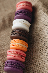 Composition of delicious colorful macaroons on sackcloth, sweet dessert