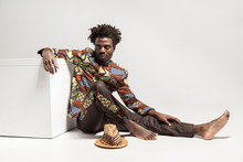 Young Adult African Man, Sitting On Floor Near Cube