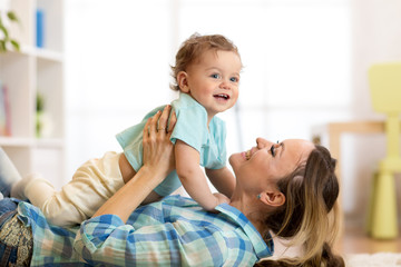 Canvas Print - Side view portrait of a happy mother lying on the floor with her baby son at home