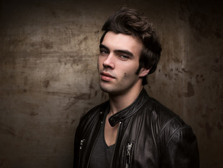 Portrait of a young man against the background of a metal wall with free space