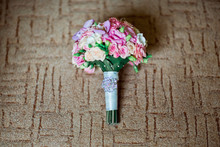 Beautiful Wedding Bouquet With Pink And Ultra Violet Flowers, Decorated With Brooch With Stones On A Brown Textile Background
