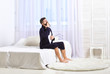 Awakening concept. Man in robe sits on bed, white curtains on background. Macho with beard and mustache sluggish getting up and yawning in morning. Guy on sleepy face yawning in morning.