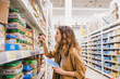 Young beautiful woman with a tablet picks baby food in a supermarket, the girl reads the composition of a product close-up