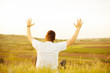 © Vulp - Man sitting on field and raising arms up at sunset