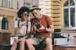 © LIGHTFIELD STUDIOS - smiling african american female traveler pointing on camera screen to boyfriend