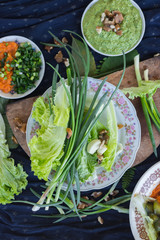 Fresh organic farm green vegetables on table: onion sprouts and salad leaves for vegetarian lunch or dinner. Source of spring vitamins and antioxidants. Raw vegan healthy food