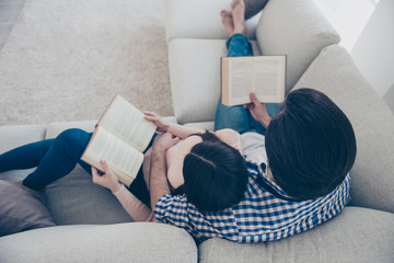 Wall Mural - Top view portrait of well-read lettered couple enjoying reading novel poem, poetry fans, lying on sofa having books in hands. Hobby free time self-development education concept