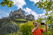 A happy young man tourist at Edinburgh Castle taking selfie on mobile phone.