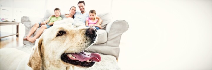 happy family sitting on couch with their pet yellow labrador in