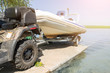 Transportation of inflatable boat on trailer. ATV quadbike moves ship to lake or river shore for launching. Beginning of water navigation and fishing season