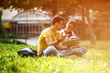 © BalanceFormCreative - Two young students sitting at the campus yard , reading book and preparing for university exam.