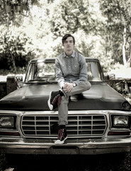 Portrait of young man sitting on old pickup truck