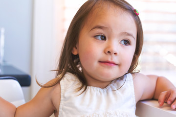 Wall Mural - Portrait of a happy toddler girl sitting at a desk