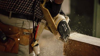 Wall Mural - carpenter in the workshop saw a piece of wood with an electric chainsaw