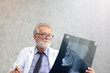 © thbangkok - Senior medical doctor or chief doctor or Surgeon are checking skull of human head via x-ray film In examination room.