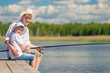 © kosmos111 - happy men with a fishing rod on a wooden pier while fishing