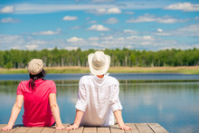 A Loving Couple Enjoying A Beautiful Lake Sitting On A Wooden Pier