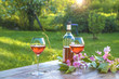 French art of living/Bottle of pink wine and two wineglasses on a rustic wooden table in a spring garden