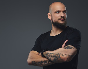 Close-up portrait of a handsome bearded athlete in a black t-shirt, posing with crossed arms in a studio.