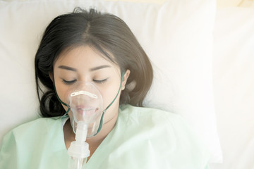 young patient alone in bed. sleeping in hospital bed. oxygen mask on her face. young beautiful chine
