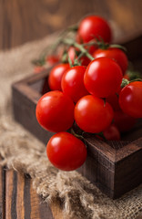 Wall Mural - Small red cherry tomatoes on rustic background. Cherry tomatoes on the vine