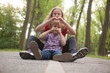© Aitor Diago - Girl making the heart sign next to her little brother sitting on a path