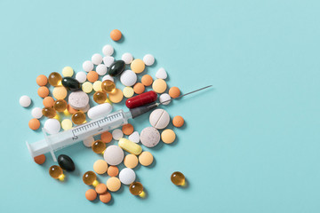 Pills and and syringe on blue background