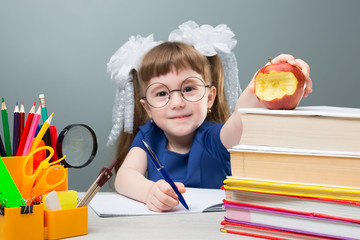 Little girl putting red bitten apple on books