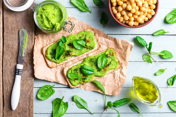 Wall Mural - Two crackers with green spinach humus on wooden table. Flat lay. Hummus concept. Food photography