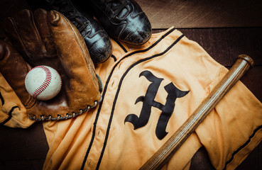 Wall Mural - A group of vintage baseball equipment, bats, gloves, baseballsand a jersey on wooden background