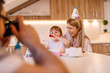 © Nebojsa - Young father is taking a photo of his daughter and her mother with birthday cake and gift box