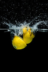 Wall Mural - close up view of fresh lemon pieces in water with splashes isolated on black